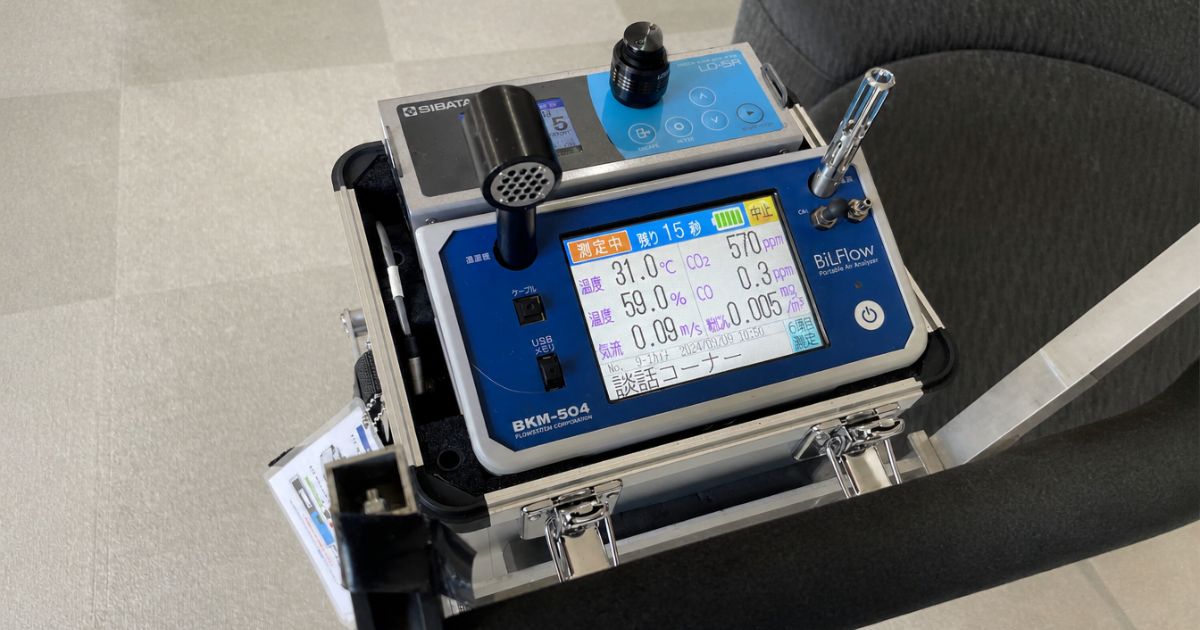 空気環境測定中のBKM-504（BilFlow Portable Air Analyser）。温度・湿度・CO₂・CO・気流・粉じんの6項目をリアルタイム表示。