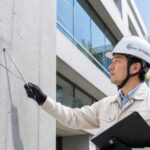 建物の外壁にあるひび割れ（クラック）を点検・調査しているコーセイ株式会社の専門技術者の様子。