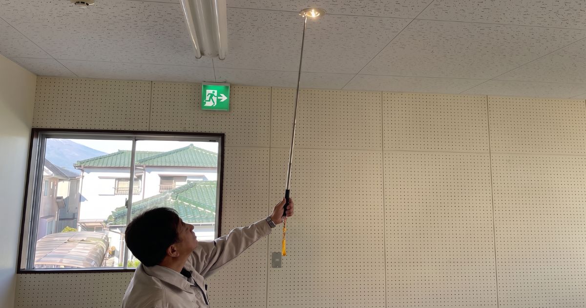 天井の非常照明装置の点灯確認検査を行う建築設備検査員